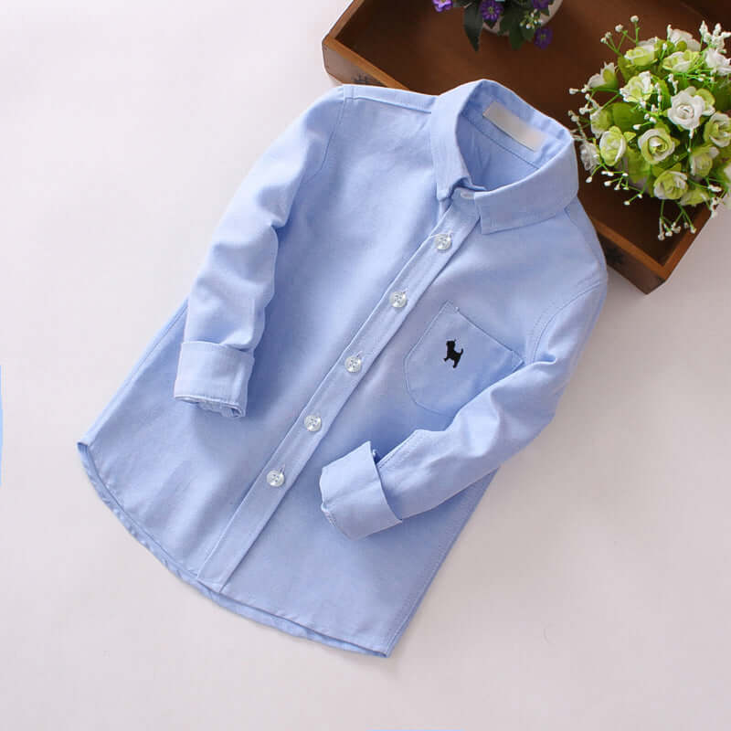 Boys’ long sleeve shirt in light blue with a lapel collar and front pocket, made of 100% cotton.