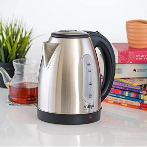 Stainless Steel Electric Kettle on a tabletop beside a glass teapot and books, showcasing its elegance and functionality.